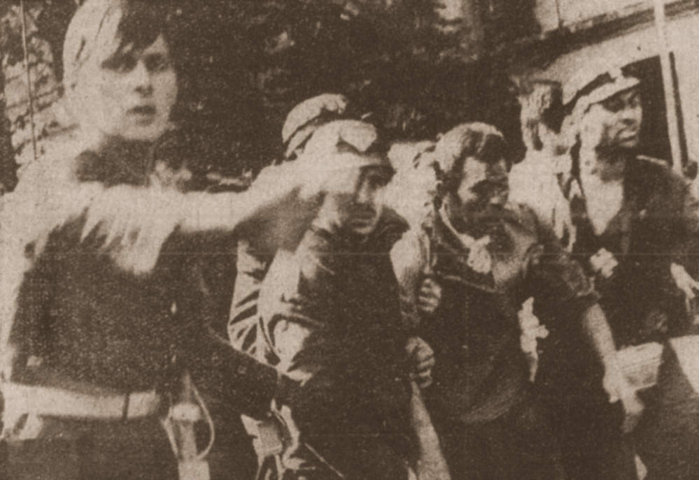 Un bărbat escortat printr-o mulțime în zona Ministerului de Interne la 14 iunie 1990